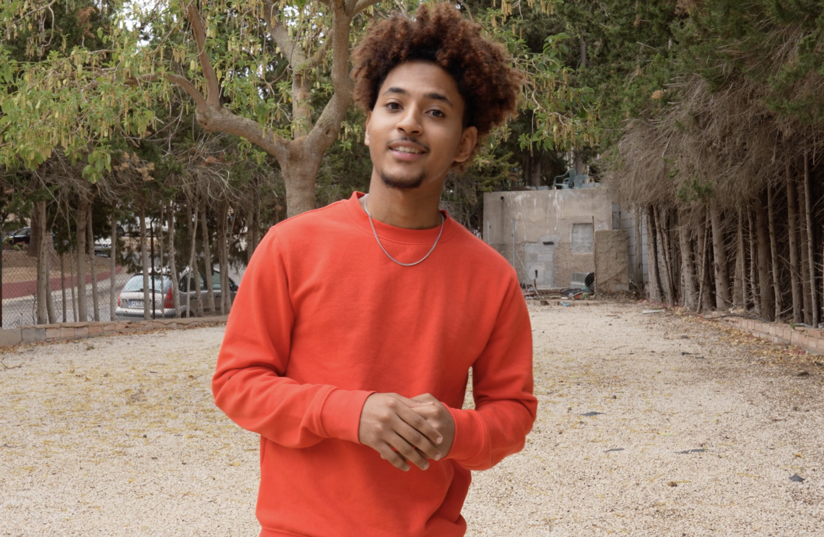 chico somalí con sueter naranja en el parque 